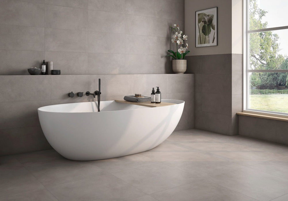 Bathroom interior featuring Etna Grey Matt 60 × 60cm porcelain wall and floor tiles, styled with a freestanding bath, black fittings, soft neutral tones, and natural light for a calm, contemporary space.