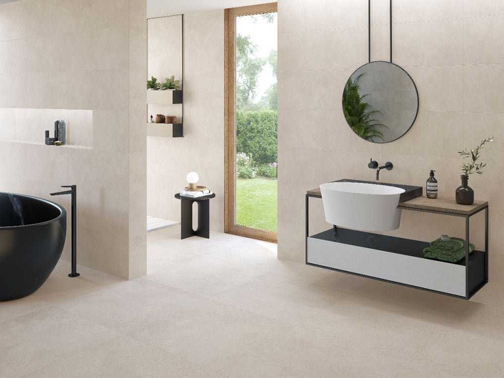 Bathroom interior featuring Etna Marfil Matt 30 × 60cm porcelain wall and floor tiles, styled with a freestanding bath, floating vanity unit, black fittings, and soft neutral tones for a calm, contemporary space.