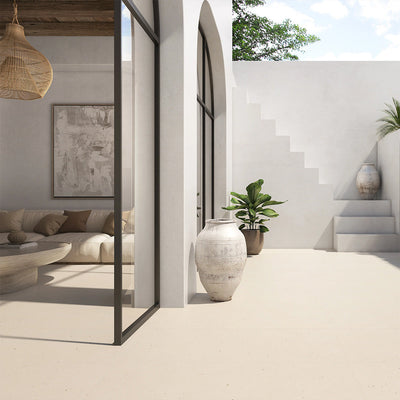 Outdoor patio featuring Etna Marfil Matt 60 × 120cm porcelain floor tiles, styled with soft neutral tones, Mediterranean-inspired architecture, large planters, and natural light for a calm, contemporary indoor-outdoor living space.