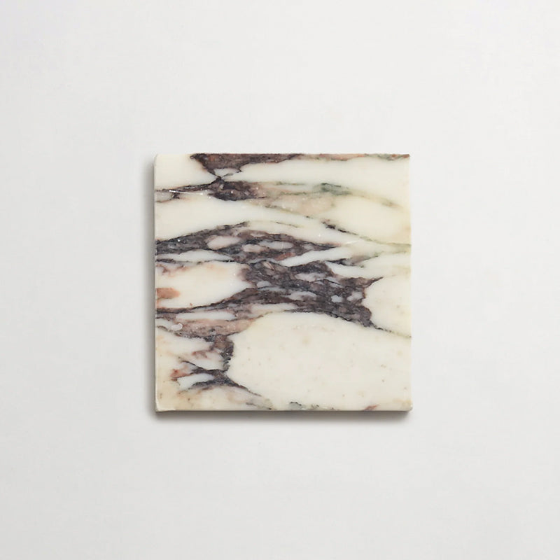 Fayrouz Calacatta Viola honed natural marble tile in a 15.2cm x 15.2cm square format, featuring a creamy white background with bold purple veining and subtle warm gold tones, creating a luxurious and timeless natural stone finish.