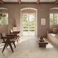 Living room featuring Flagstone Beige Tumbled Travertine 50 × 100cm porcelain floor tiles, styled with rustic wood furniture, soft neutral tones, and natural light for a warm, Mediterranean-inspired space.