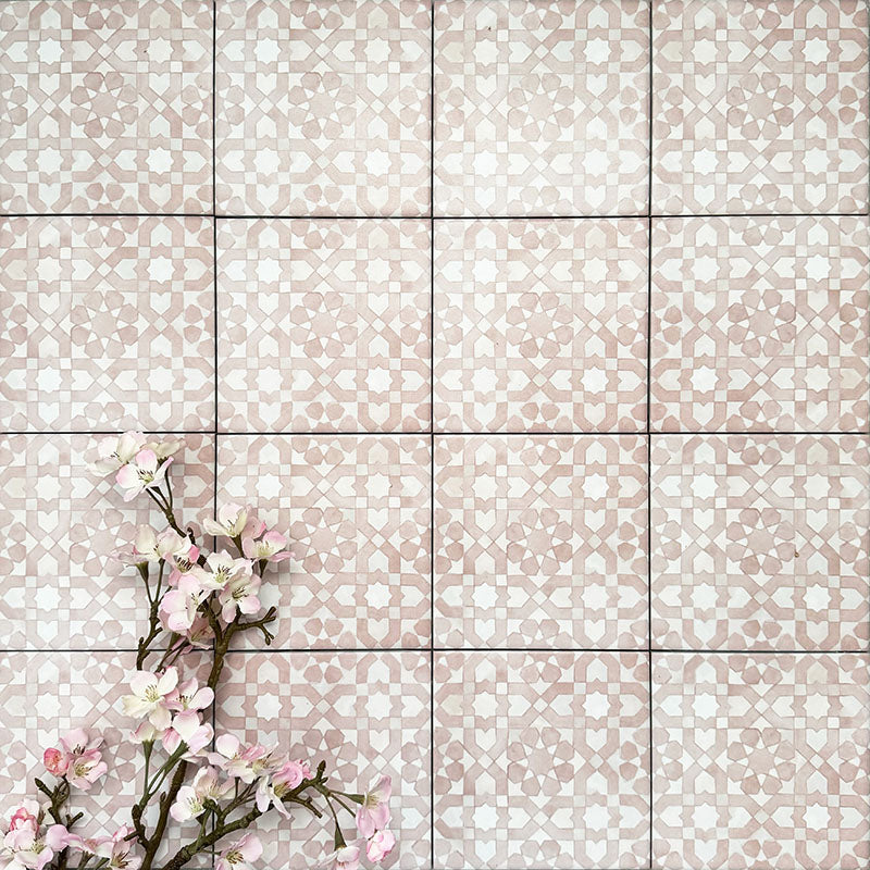 Berber Tetuan Rose 15×15cm Moroccan-style porcelain tiles laid in a grid pattern, showcasing a soft pink and cream geometric design with decorative floral styling.