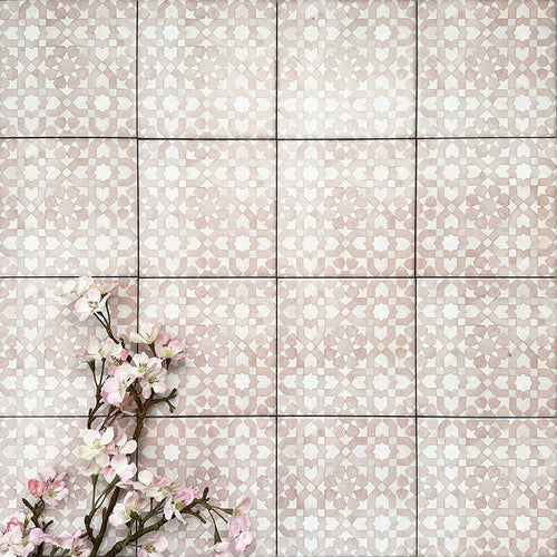 Berber Tetuan Rose 15×15cm Moroccan-style porcelain tiles laid in a grid pattern, showcasing a soft pink and cream geometric design with decorative floral styling.