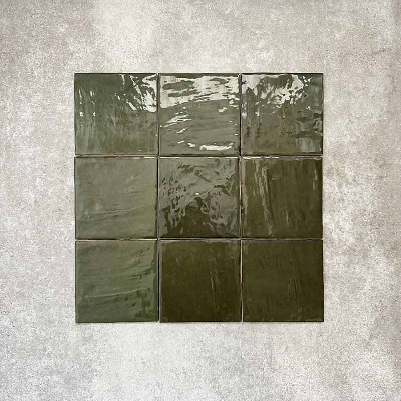 Flat lay showcasing Zellige Botanical Green Square 13.2 × 13.2cm Moroccan-style ceramic tiles, featuring rich botanical green tones, a glossy handcrafted zellige-effect glaze and natural tonal variation, arranged on a neutral textured background to highlight their artisanal character.