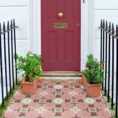 Nantes Rose Pink Moroccan-style tiles laid at a front entrance, creating a decorative tiled doorstep. The 20x20cm patterned tiles feature soft pink floral motifs with cream circular detailing and subtle geometric accents, beautifully complementing the deep red front door and classic townhouse exterior.