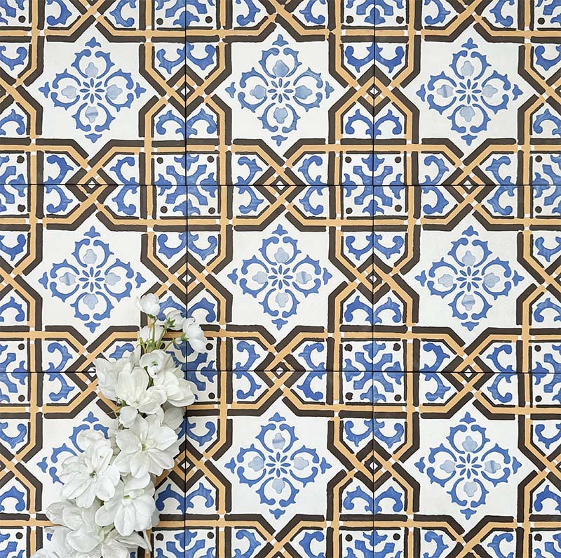 Viscount Maestro 20×20cm Victorian-style porcelain wall and floor tiles laid in a repeating ornate geometric pattern with floral detailing in blue, white and warm ochre tones, shown as a full tile layout with subtle tonal variation and floral styling.