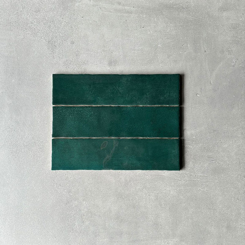 Three Nairobi gloss moss green handmade-effect tiles shown together, highlighting natural tonal variation, lightly textured glazing and the gently uneven edges of the rustic finish.