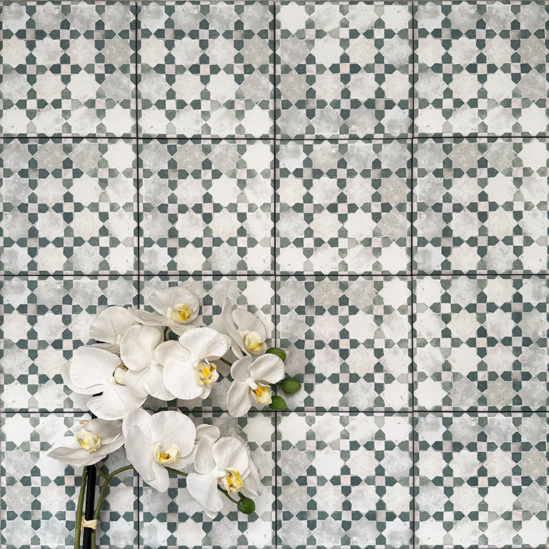 Berber Mequinez Green 15×15cm Moroccan-style porcelain tiles laid in a grid pattern, showcasing a soft green and cream geometric design with decorative floral styling.
