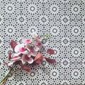 Fez Mini Winter Moroccan-style porcelain tiles laid in a repeating pattern, featuring a crisp black and white geometric star design. The 15 × 15cm encaustic-effect tiles create a bold yet timeless look, with intricate detailing that adds depth and rhythm across the surface. Styled with soft pink florals for contrast, this design is ideal for statement floors, splashbacks, or feature walls in both modern and classic interiors.