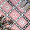Gilgamesh Pink Moroccan style 20x20cm patterned tiles, shown in a flat lay with decorative foliage to highlight the geometric star design in soft pink, black and white.