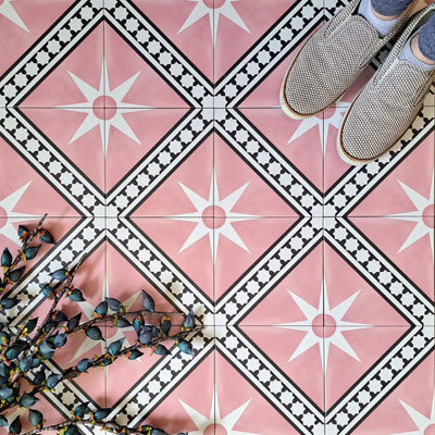 Gilgamesh Pink Moroccan style 20x20cm patterned tiles, shown in a flat lay with decorative foliage to highlight the geometric star design in soft pink, black and white.