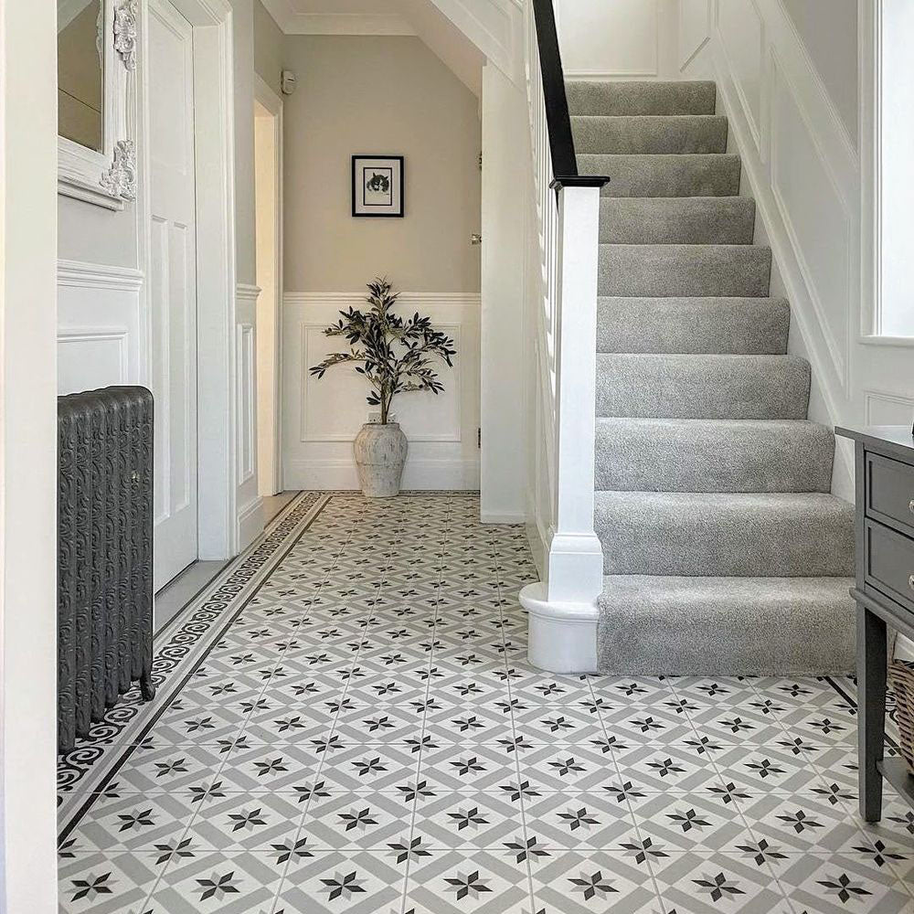 Hallway featuring Canterbury Star Victorian-style porcelain floor tiles in a 20 × 20cm format, laid in a repeating geometric star pattern with a decorative border, paired with a carpeted staircase, traditional panelling and classic period details for a timeless entrance.