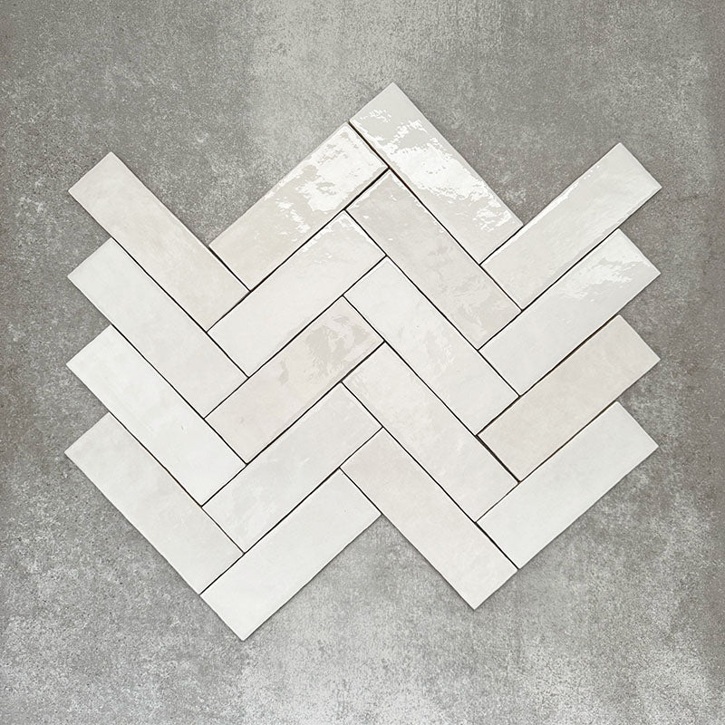 Zellige White brick tiles arranged in a herringbone pattern, featuring a glossy white finish with natural tonal variation.