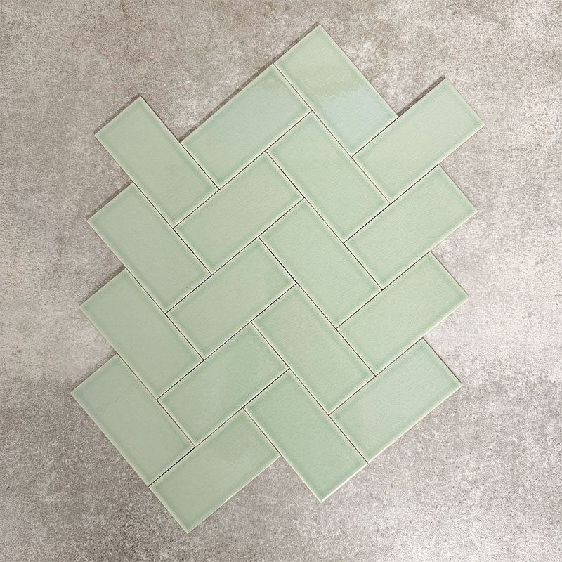 Pimlico Lime Green 7.5 × 15cm ceramic tiles with a crackle glaze finish, shown in a herringbone layout highlighting soft green tones, subtle texture and versatile design options for bathroom or kitchen walls.