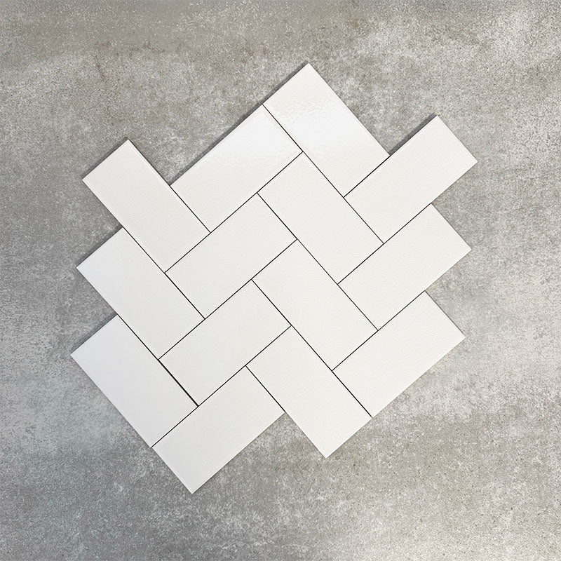 Pimlico White 7.5 × 15cm ceramic wall tiles with a crackle glaze finish, shown in a herringbone layout that highlights soft white tones, subtle texture and versatile design options for kitchens and bathrooms.