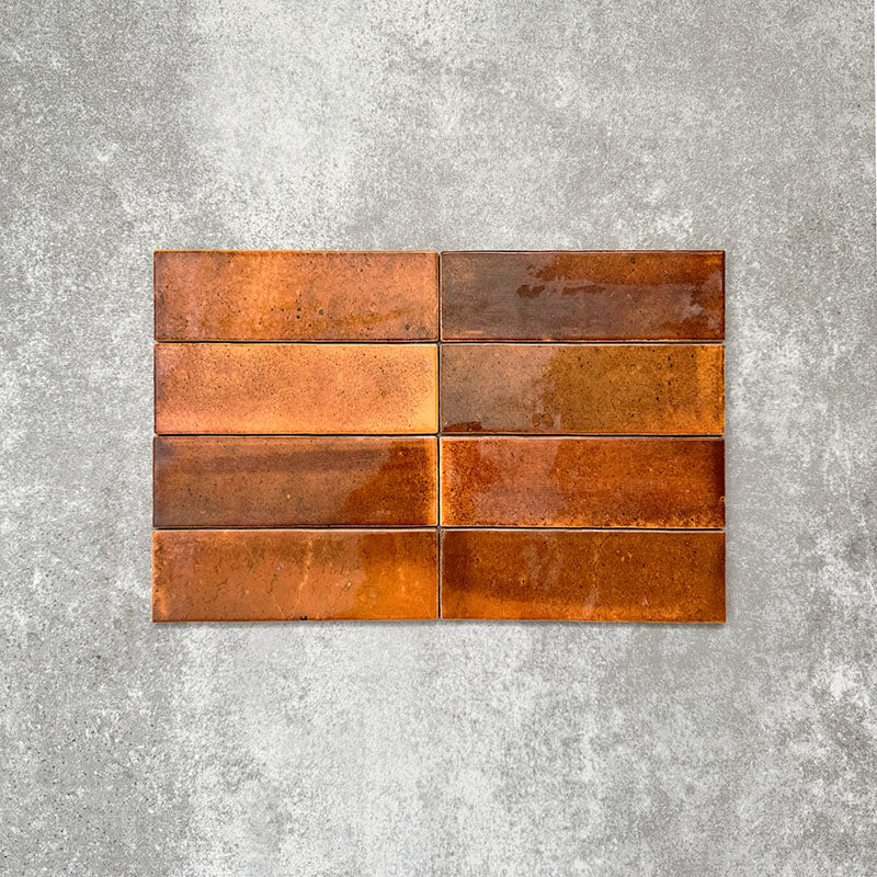 Saigon Amber Brick Wall tiles laid horizontally, featuring Moroccan-style 5.1 × 16.1cm glossy ceramic tiles with warm amber and copper colour variations.