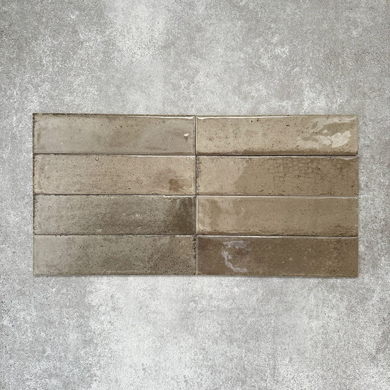 Allegra Sage Green Gloss Brick ceramic tiles in a 6 × 25cm format, laid horizontally to highlight the muted green tones, glossy finish and subtle handmade-style surface variation.