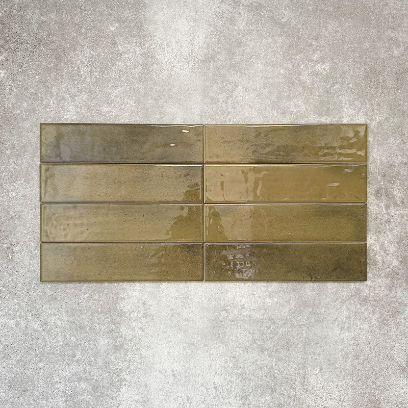 Allegra Daisy Green Gloss Brick ceramic tiles in a 6 × 25cm format, laid horizontally to highlight the rich green tones, glossy finish and subtle handmade-style surface variation.