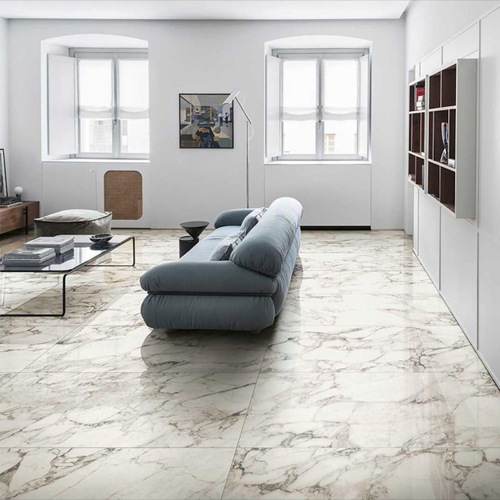 Living room featuring Hudson Calacatta Matt Marble 60 × 60cm porcelain floor tiles, showcasing a soft white base with flowing grey veining, paired with minimalist furnishings, light walls, and natural light to create a calm, open, contemporary space.