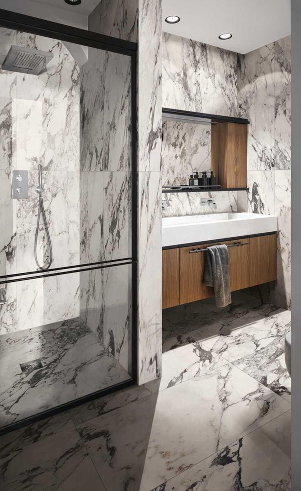 Bathroom interior featuring Hudson Capraia Matt Marble 60 × 120cm porcelain wall tiles, showcasing a crisp white base with bold, dramatic grey veining, paired with black-framed shower detailing and warm wood cabinetry for a striking, contemporary contrast.