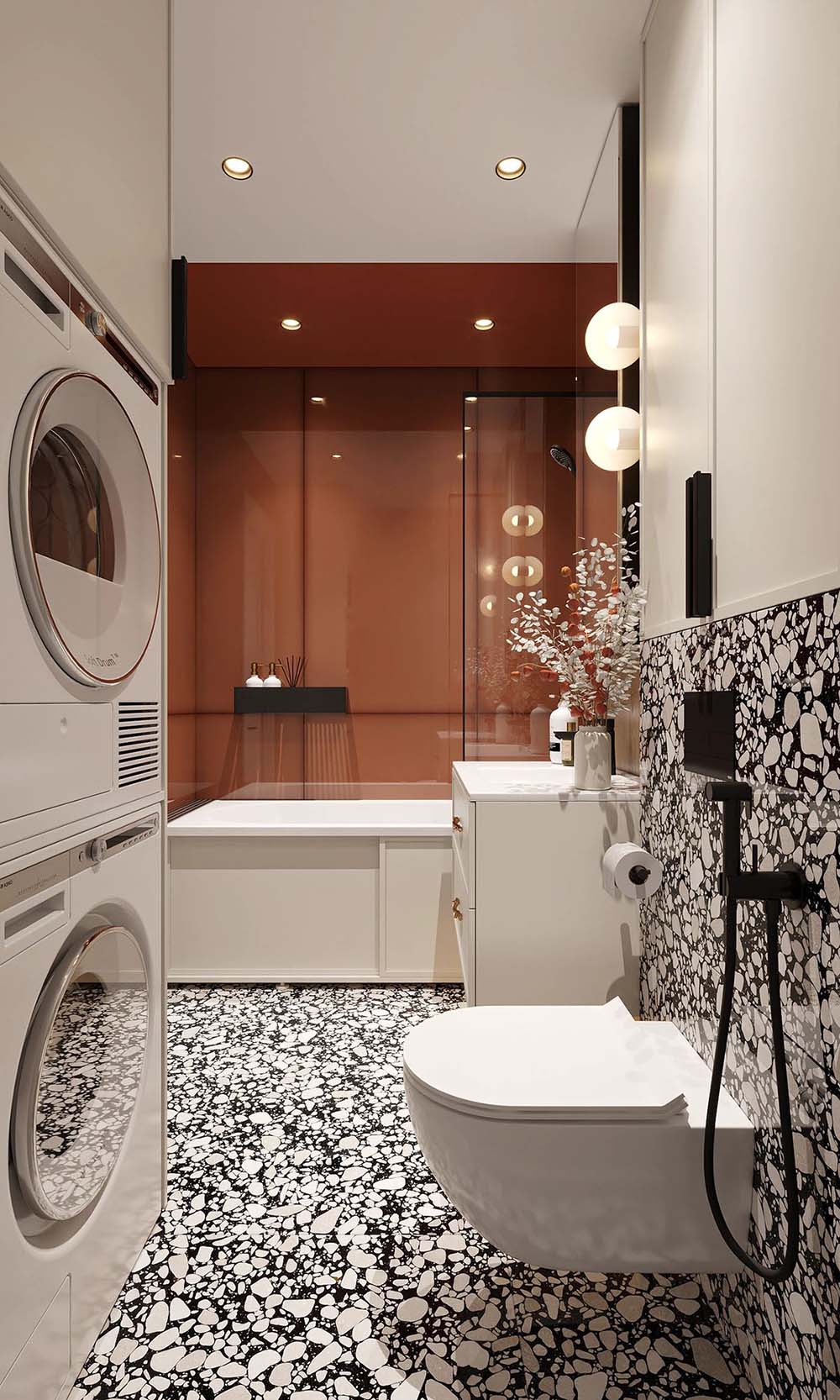 Bathroom setting featuring Shards Terrazzo Nero 59x59cm matt porcelain wall and floor tiles, showcasing a bold terrazzo effect with large white stone fragments set against a deep black base, used across both floor and feature wall, paired with crisp white sanitaryware, warm terracotta tones and soft lighting for a balanced, contemporary contrast.
