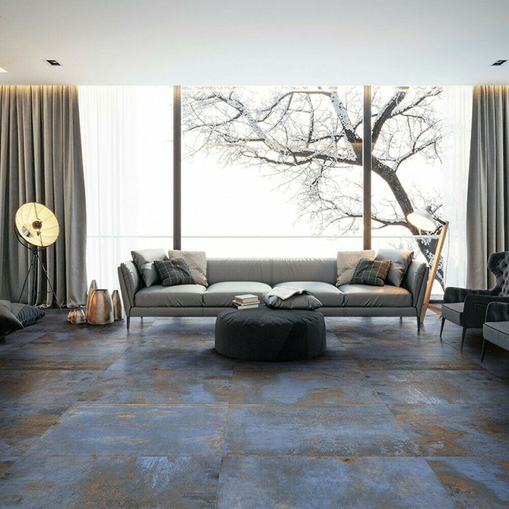 Living room interior featuring Iron Blue Oxide Metallic 30 × 60cm porcelain floor tiles, styled with deep blue tones layered with warm oxidised variation and a softly textured metallic effect surface, paired with contemporary furnishings and soft neutral fabrics for a moody, industrial-inspired finish.