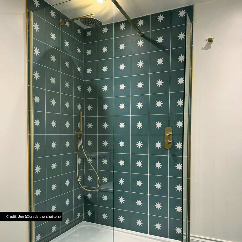 Bathroom interior featuring Supernova Decor Green patterned wall tiles with white star motif, installed in a walk-in shower with brass fixtures and glass enclosure in a modern bathroom setting.