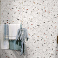 Bathroom wall featuring Jericho White Terrazzo Hexagon 25 × 22cm porcelain tiles, with a clean white base and scattered multicoloured aggregate chips, laid in a honeycomb pattern and paired with soft textiles for a fresh, contemporary look.