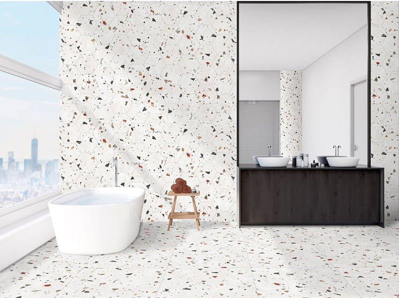Bathroom interior featuring Jericho White Terrazzo Hexagon 25 × 22cm porcelain wall and floor tiles, with a crisp white base and multicoloured aggregate chips, laid in a continuous honeycomb pattern and paired with a freestanding bath and dark wood vanity for a clean, contemporary contrast.