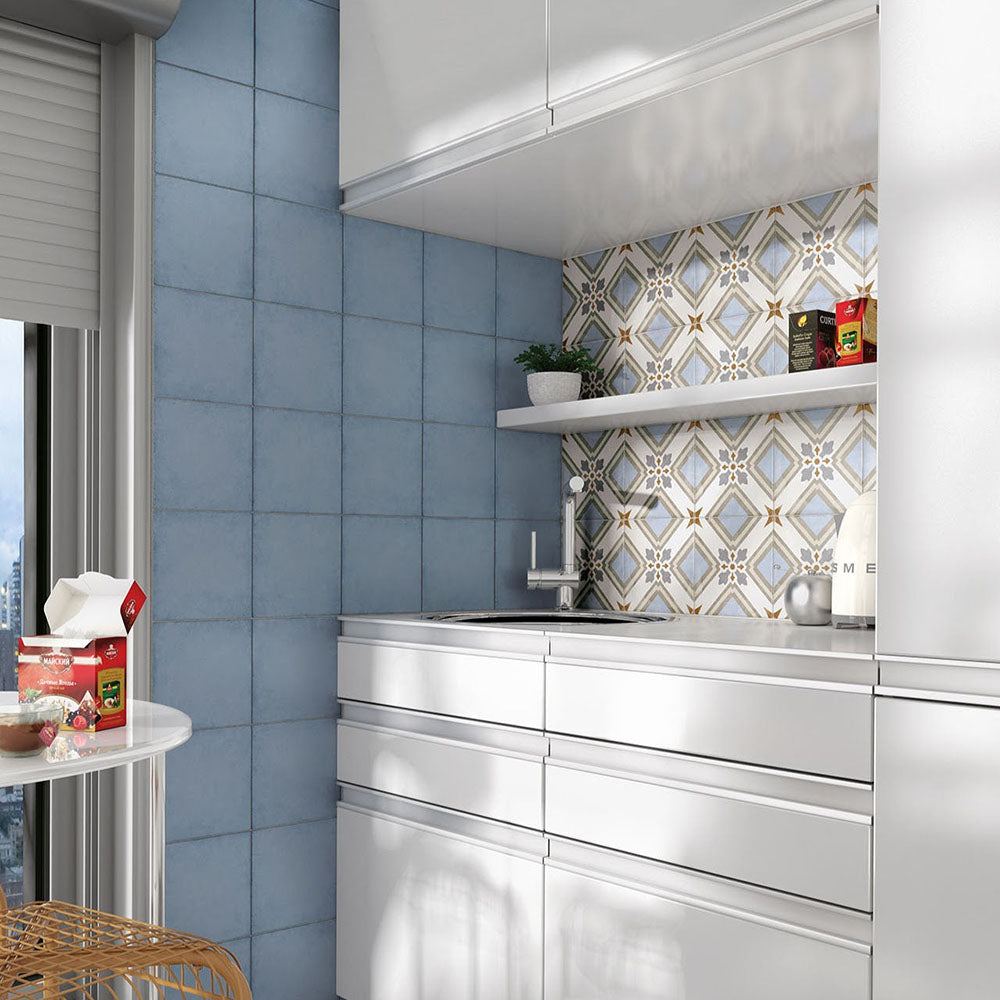 Victorian-style kitchen featuring Viscount Turner 20×20cm porcelain wall and floor tiles with a blue, beige and white geometric pattern, styled as a decorative splashback alongside soft blue wall tiles, sleek white cabinetry and open shelving for a bright, contemporary look.