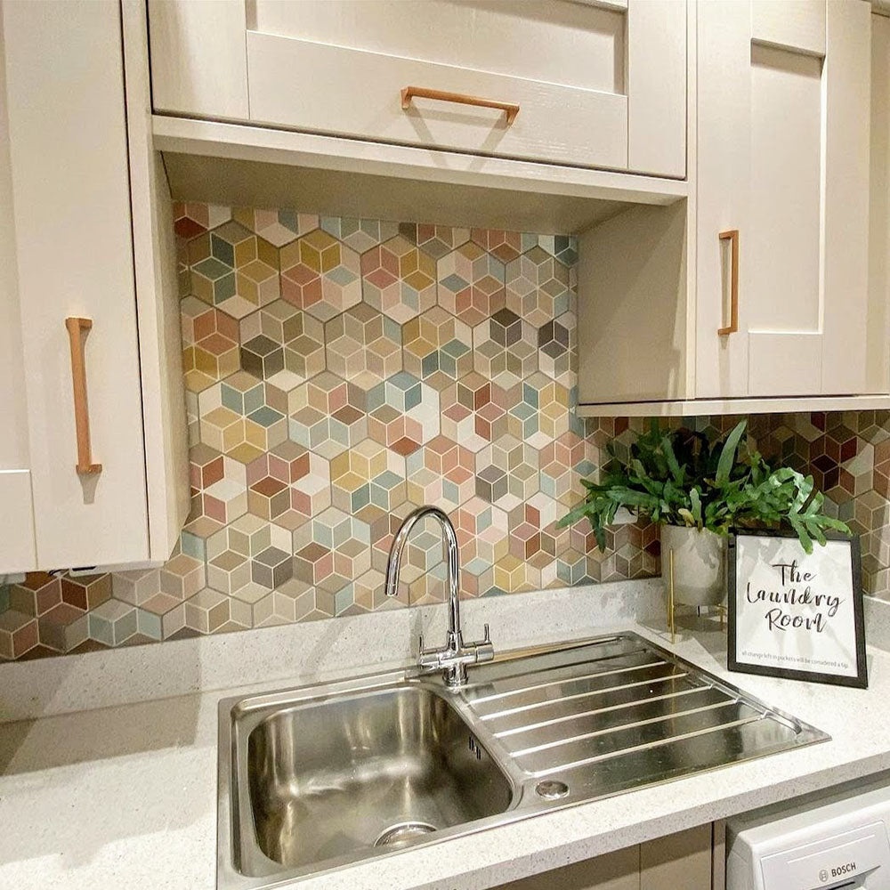 Kitchen splashback featuring Athens Multicoloured Hexagon Patchwork 17x15cm Moroccan-style tiles, displaying a geometric cube-effect pattern in soft pastel and earthy tones, paired with light cabinetry and warm wood handles for a playful yet contemporary finish.