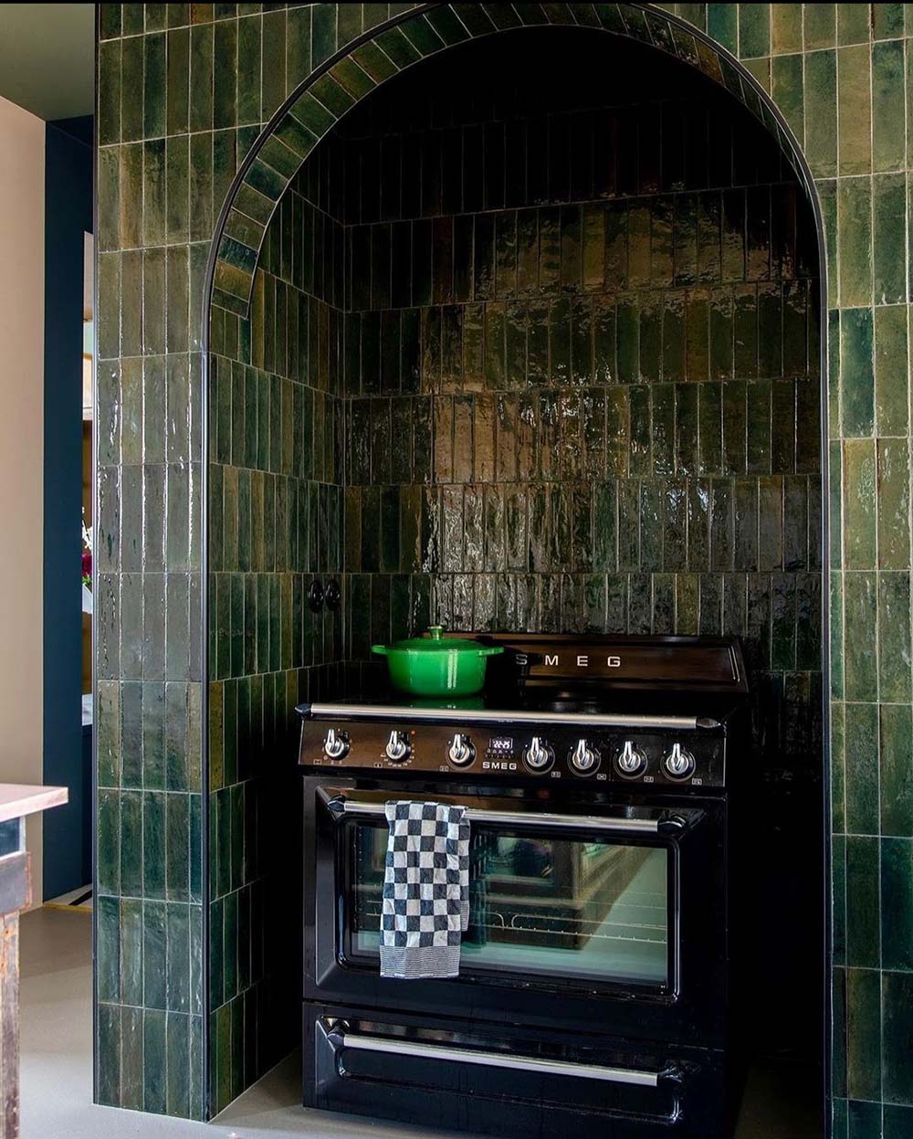 Kitchen setting featuring Levent Green 6x24cm porcelain wall and floor tiles, showcasing rich tonal variation and a glossy finish, installed in a striking arched alcove to frame the cooking area and create a bold, characterful focal point.