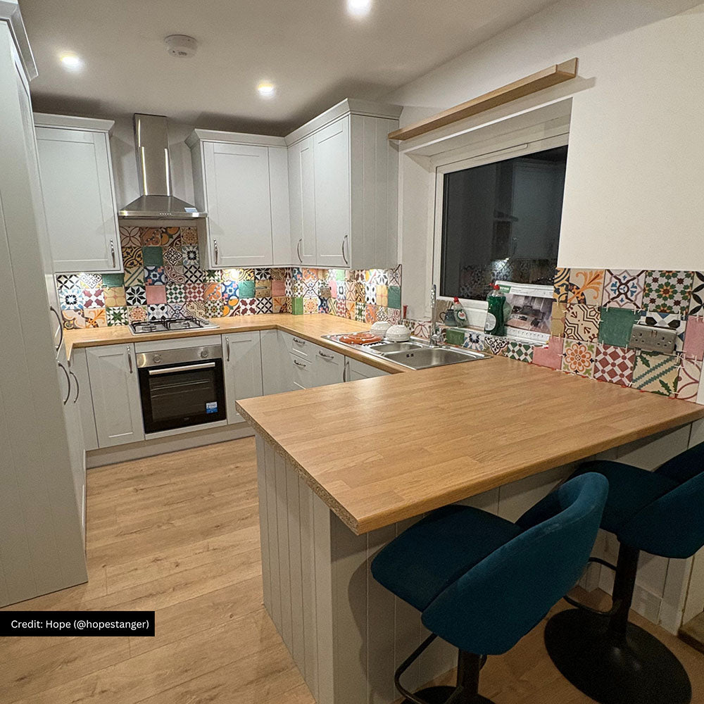 Kitchen featuring Fayrouz Mini Patchwork 15×15cm Moroccan-style porcelain tiles used as a colourful splashback, showcasing an eclectic mix of geometric and floral patterns in soft pink, sage green, terracotta, mustard yellow, navy and neutral tones, paired with light grey shaker cabinets and warm wood worktops for a striking yet balanced finish.