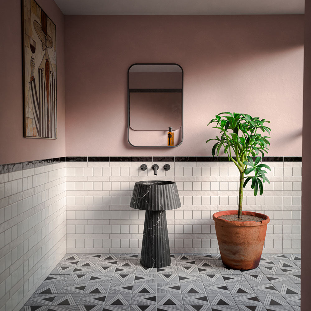 Bathroom featuring Levent Antique White Brick gloss porcelain wall tiles in 6cm x 24cm, showcasing soft antique white tones with a glossy finish, paired with a black marble border tile, blush pink walls, a fluted black marble pedestal basin, matt black brassware and a contemporary interior.
