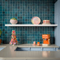 Kitchen splashback featuring Levent Blue Square 10cm x 10cm gloss porcelain wall tiles, showcasing rich blue tones with subtle handmade-effect shade variation, paired with pale blue cabinetry, light stone worktops, open shelving and vibrant contemporary accessories.
