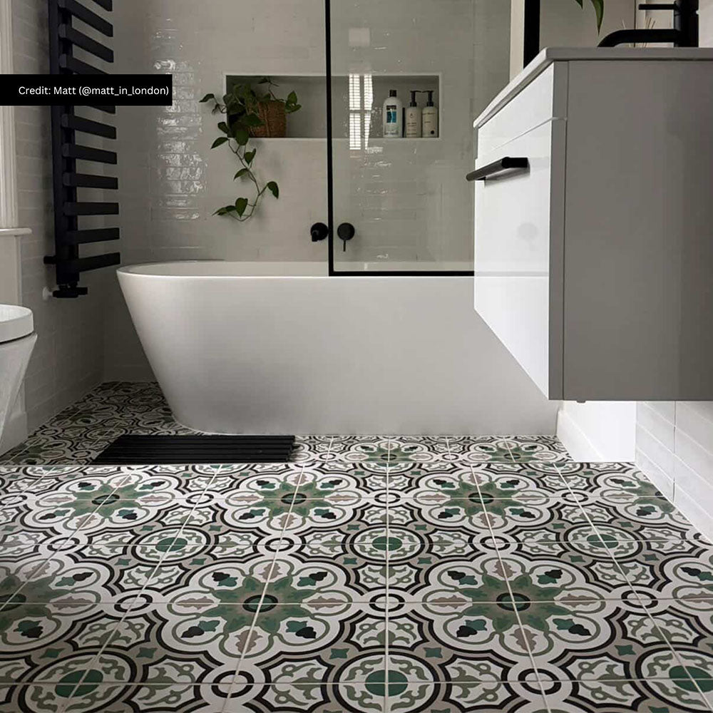 Bathroom interior featuring London Streets Bond Street 20 × 20cm Victorian Moroccan-style porcelain floor tiles, styled with an intricate green, grey, and black patterned design, paired with glossy white wall tiles, matte black fittings, and a freestanding bath for a bold, timeless look.