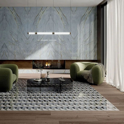 Living room interior featuring Lucca Diamond Tips 3D Décor 60 × 120cm porcelain wall and floor tiles, combining geometric patterned flooring with marble-effect feature walls, styled with olive green lounge chairs, warm wood flooring, and a contemporary fireplace.