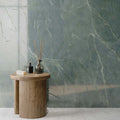 Interior featuring Lucca Ocean Green Lux 3D 60 × 120cm porcelain wall tiles, showcasing rich green marble-effect tones with delicate veining, paired with warm wood furniture and contemporary spa-inspired styling.