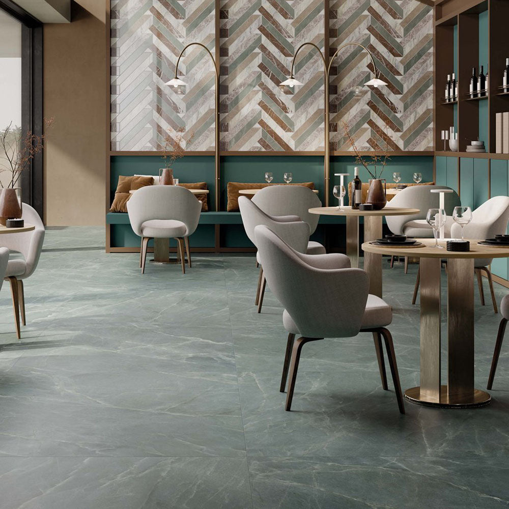 Restaurant interior featuring Lucca Ocean Green Natural Matt 60 × 120cm porcelain floor tiles, styled with soft green marble-effect tones, contemporary furniture, brass accents, and warm modern hospitality-inspired interiors.