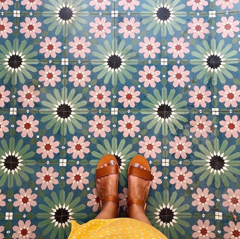 Floor featuring Fez Autumn 20x20cm Moroccan-style porcelain tiles, showcasing a rich geometric star pattern in earthy green, blue and blush pink tones, styled with tan leather sandals for a warm, bohemian look.