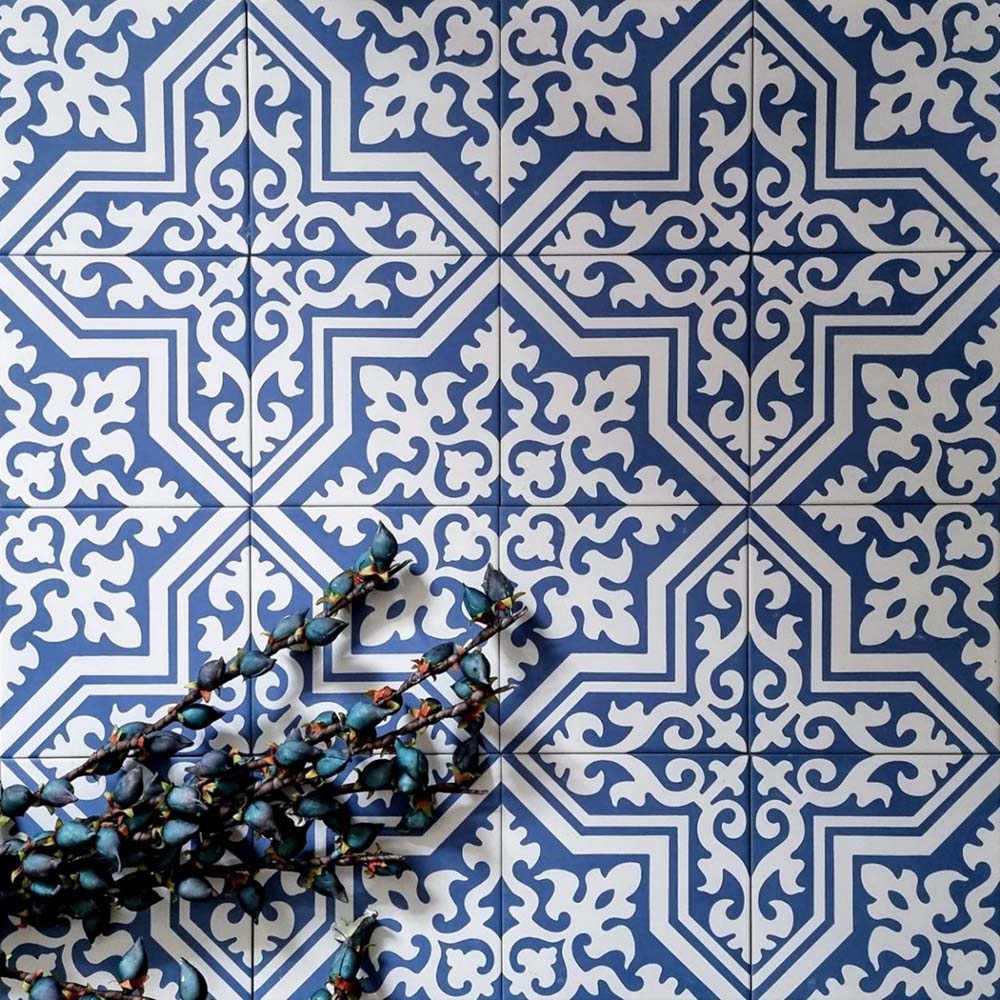 Overhead view of London Streets Thornton Place 20x20cm Victorian Moroccan style porcelain tiles arranged in a repeating blue and white patterned layout, styled with decorative foliage to highlight the intricate traditional Victorian-inspired floor design.
