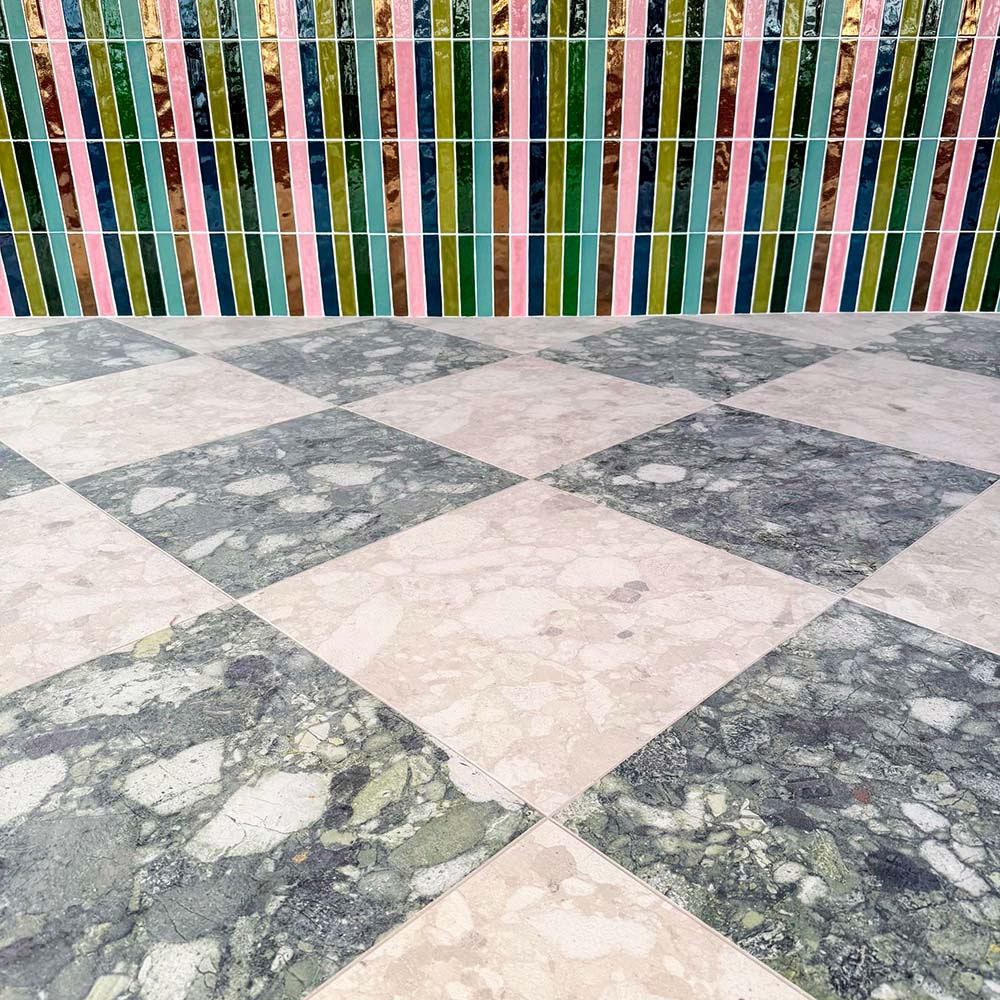 Interior space featuring Venice Ivory terrazzo tiles in a matt finish, 60x60cm, laid in a diamond pattern on the floor, paired with colourful vertical wall tiles for a bold, contemporary contrast.