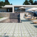 Modern outdoor pool area featuring Mediterraneo Olbia 2cm patterned outdoor slabs 50 × 100cm, showcasing a faded Mediterranean-inspired design in soft green and neutral tones, paired with sun loungers and contemporary architecture.
