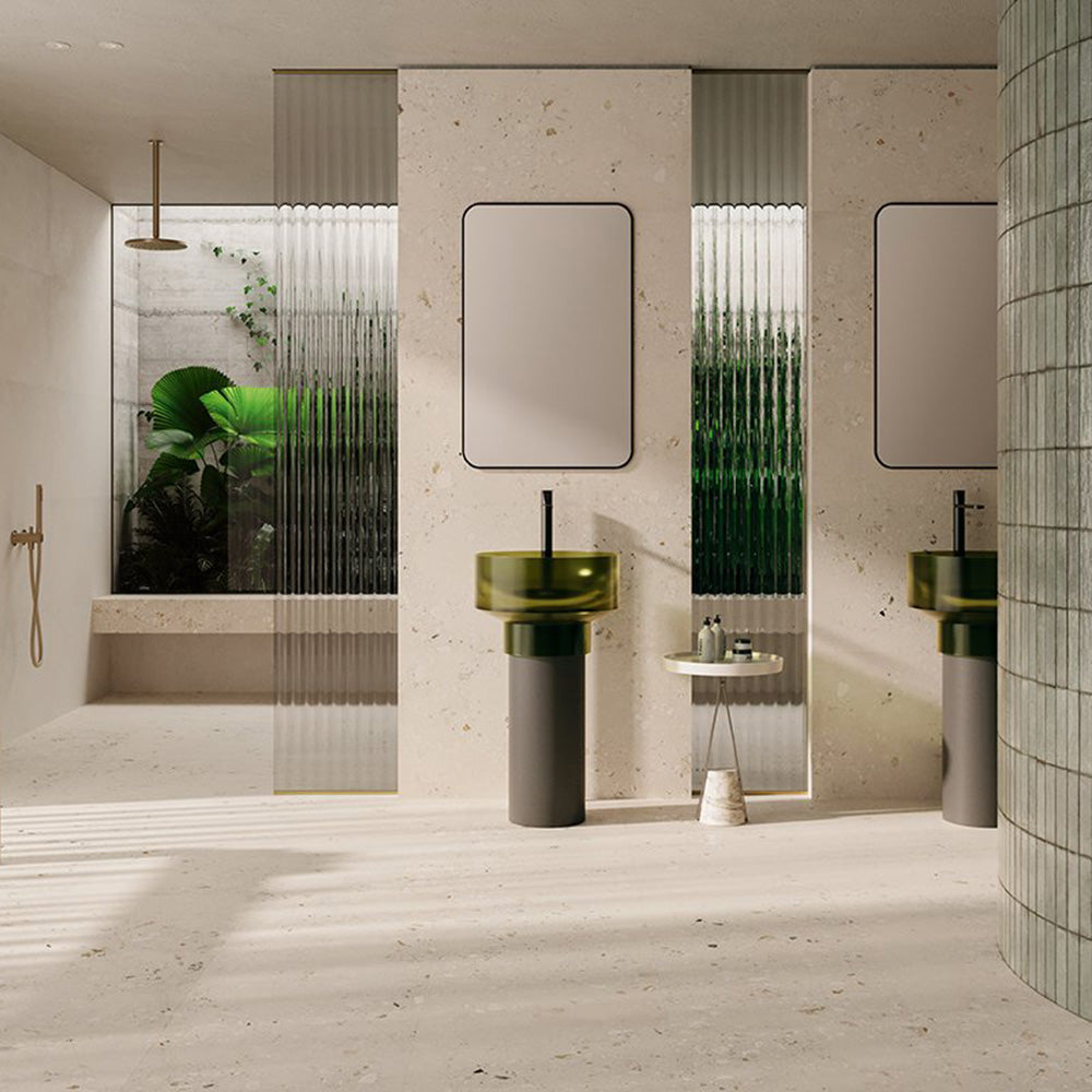 Contemporary bathroom featuring Melange Light Cosmo Stone wall and floor tiles 60 × 120cm, showcasing soft ivory stone-effect tones with subtle aggregate detailing, paired with green glass basins, fluted glass panels, and minimalist fittings.