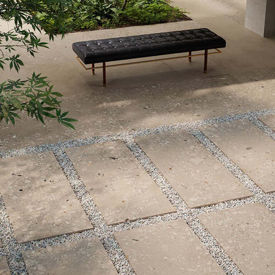 Modern outdoor seating area featuring Melange Sand 20mm thick outdoor Cosmo Stone tile slabs 60 × 120cm, showcasing warm sand-toned terrazzo-inspired detailing, paired with gravel pathways, contemporary landscaping, and minimalist outdoor furniture.