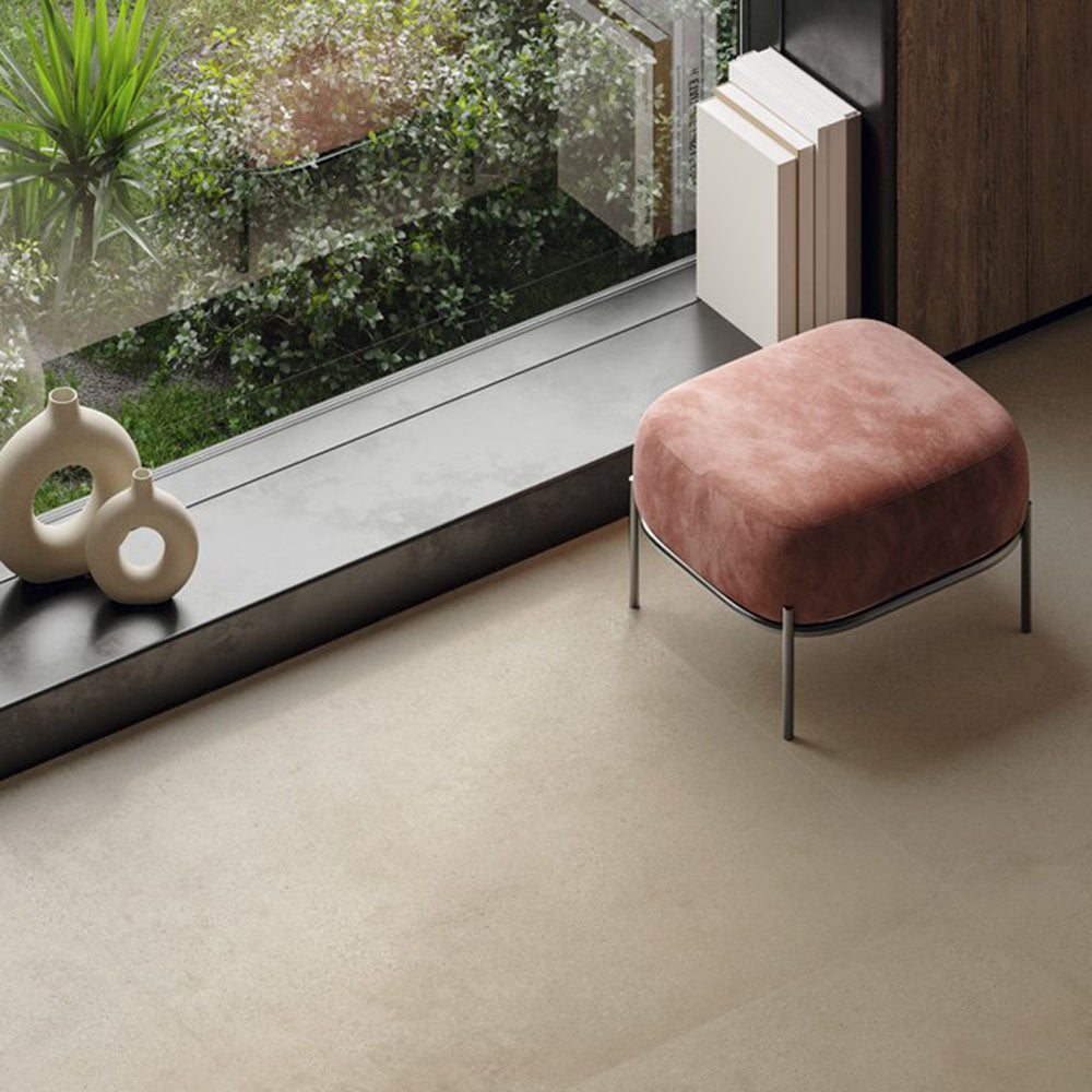 Contemporary interior featuring Melange Sand concrete-effect wall and floor tiles 60 × 60cm, showcasing warm sand-toned concrete-inspired detailing with subtle texture, paired with minimalist décor, dark wood finishes, and soft blush seating.
