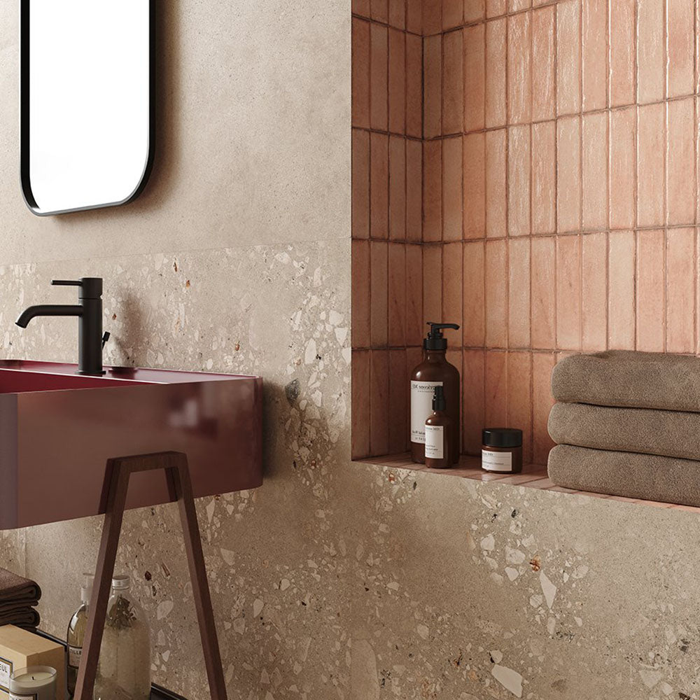 Contemporary bathroom featuring Melange Sand concrete-effect wall and floor tiles 60 × 60cm, showcasing warm sand-toned concrete-inspired detailing with subtle texture, paired with terrazzo accents, blush pink features, and minimalist décor.