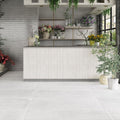 Bright botanical interior featuring Melody Cement White 30 × 60cm concrete-effect porcelain floor tiles, showcasing soft white tones and a subtle industrial texture, paired with natural wood finishes, layered greenery, and light-filled contemporary styling.