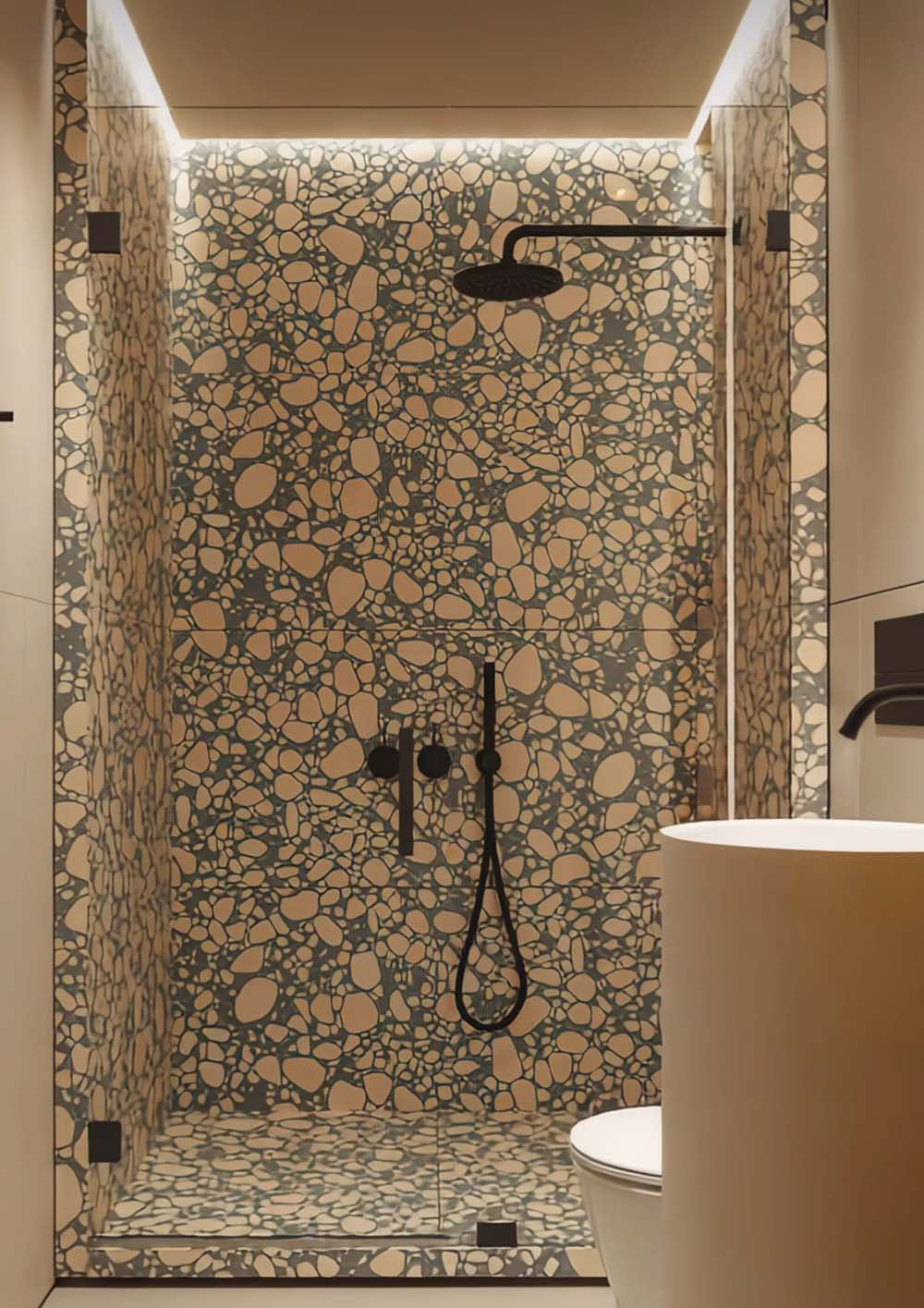 Walk-in shower featuring Melody POP Terrazzo Green 60 × 120cm terrazzo-effect porcelain wall and floor tiles, showcasing soft blush pink stone fragments against a muted green base, paired with matte black fittings and ambient lighting for a bold contemporary bathroom design.