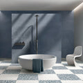 Contemporary bathroom featuring Melody POP Terrazzo White 60 × 60cm terrazzo-effect porcelain floor tiles, laid in a bold blue and white chequerboard design and paired with deep blue wall tiles, a freestanding bath, and minimalist fittings for a striking modern interior.